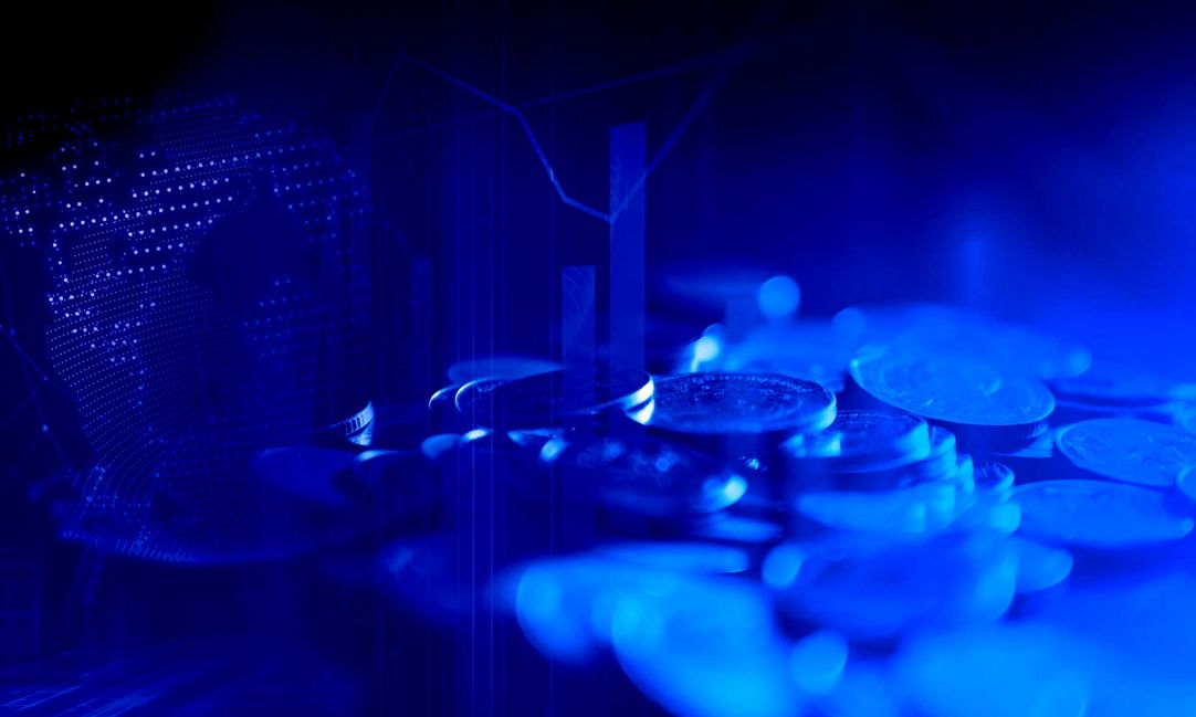 a blue tinted composite image featuing shiny coins, overlaid candlestick stock market graphs, and lit up dots representing finance sector cyber security
